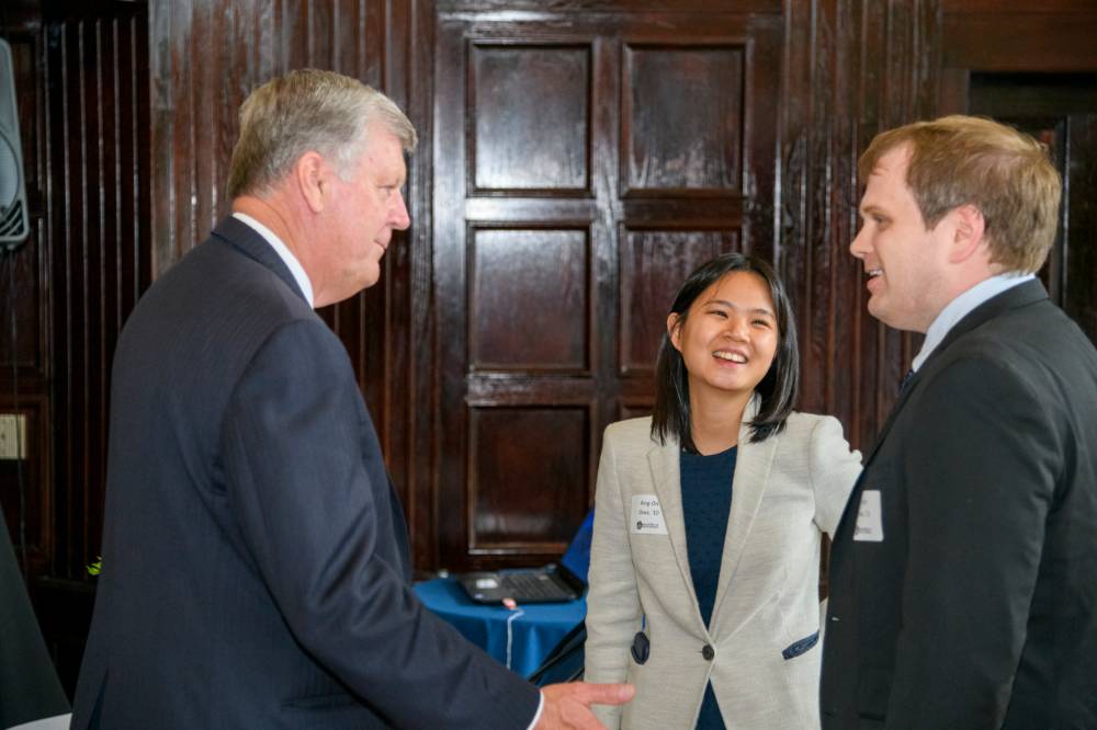 two alumni shake hands with President Haas